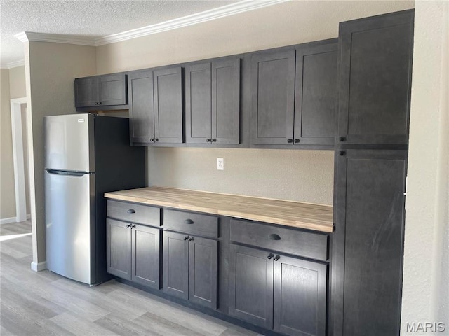 61 Wildwood Ter, Sullivan, MO 63080 - kitchen with freestanding refrigerator, crown molding, light wood-type flooring, light countertops, and a textured ceiling
