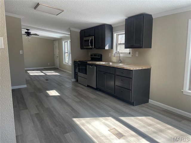 61 Wildwood Ter, Sullivan, MO 63080 - kitchen with appliances with stainless steel finishes, a sink, a textured ceiling, light countertops, and light wood finished floors