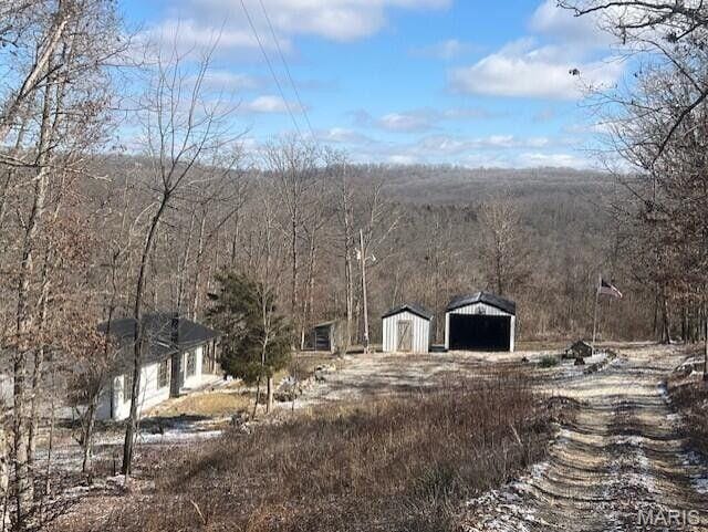 11498 M-Weatherman Dr, Mountain Grove, MO 65711 - view of home's exterior featuring an outbuilding, a detached garage, and a wooded view
