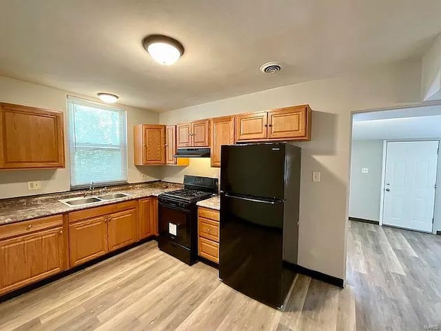 517 Mascoutah Ave, Belleville, IL 62220 - kitchen with black appliances, under cabinet range hood, a sink, light wood finished floors, and brown cabinetry