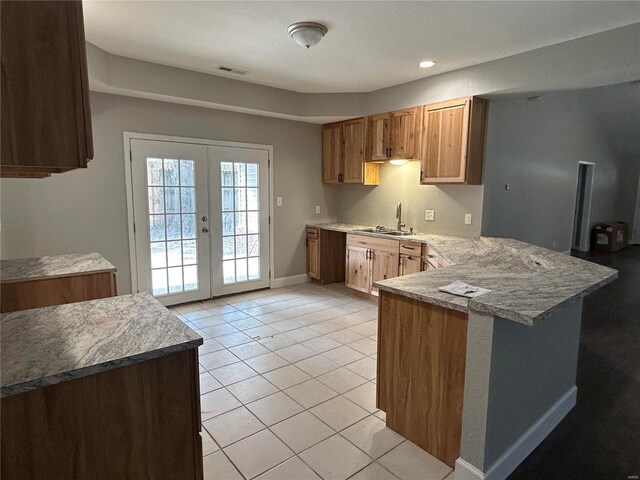 404 N Everett St, Kennett, MO 63857 - kitchen with a peninsula, a sink, light tile patterned flooring, french doors, and light countertops