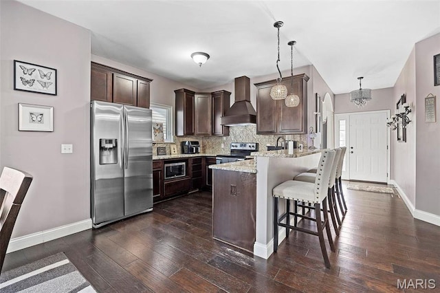 4028 Montague Cir Unit 4, Saint Charles, MO 63304 - kitchen with stainless steel appliances, wall chimney range hood, dark brown cabinets, a peninsula, and dark wood-style flooring