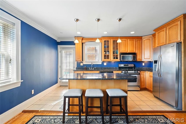 7570 Byron Pl Unit 3E, Saint Louis, MO 63105 - kitchen featuring stainless steel appliances, a center island, a breakfast bar area, crown molding, and glass insert cabinets