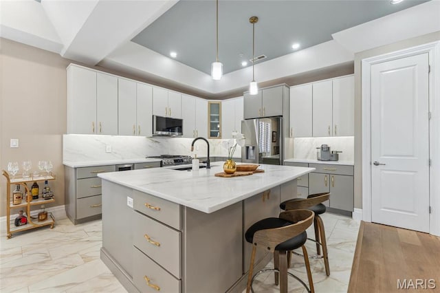 4411 Mcpherson Ave Unit 3, Saint Louis, MO 63108 - kitchen featuring stainless steel appliances, light marble finish floors, gray cabinetry, a center island with sink, and recessed lighting