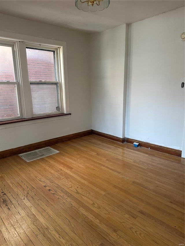 3923 Gravois Ave, Saint Louis, MO 63116 - unfurnished room featuring light wood-style floors, baseboards, and a chandelier