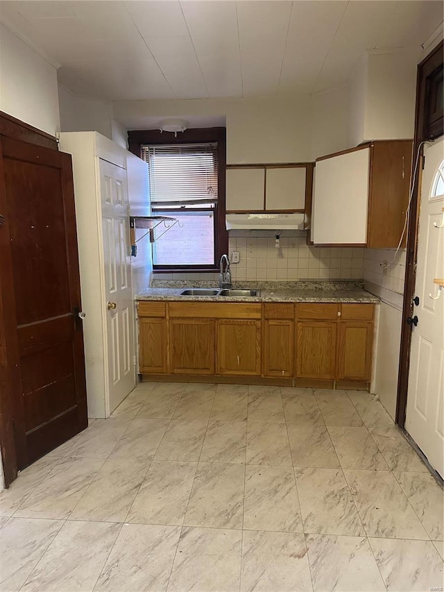 3923 Gravois Ave, Saint Louis, MO 63116 - kitchen with a sink, brown cabinetry, under cabinet range hood, and backsplash