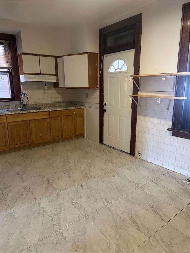 3923 Gravois Ave, Saint Louis, MO 63116 - kitchen with a sink, under cabinet range hood, brown cabinetry, healthy amount of natural light, and tile walls