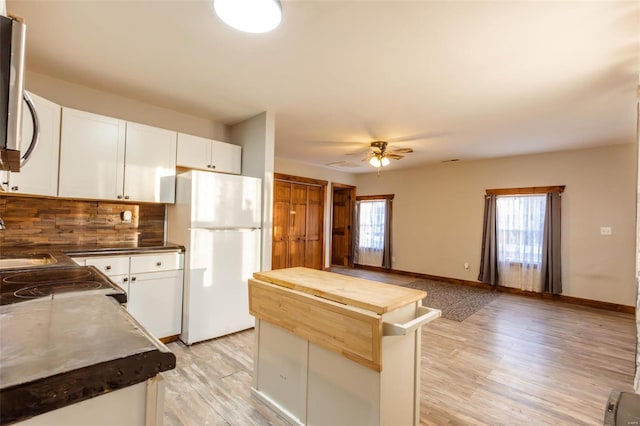 kitchen featuring freestanding refrigerator, wood counters, tasteful backsplash, ceiling fan, and light wood finished floors