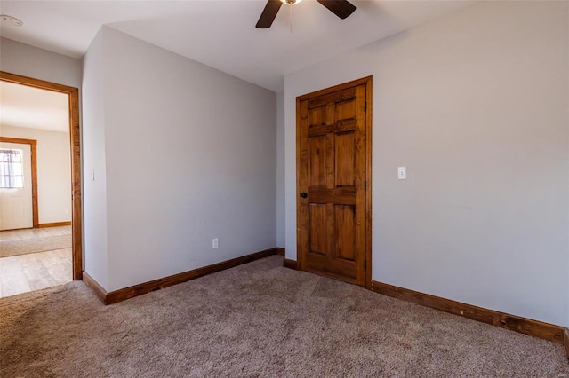 carpeted spare room featuring a ceiling fan and baseboards