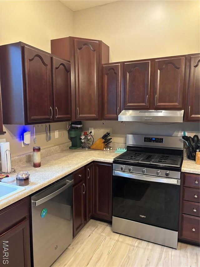 911 Grand Ave, Edwardsville, IL 62025 - kitchen featuring stainless steel appliances, under cabinet range hood, light countertops, light wood finished floors, and dark brown cabinets