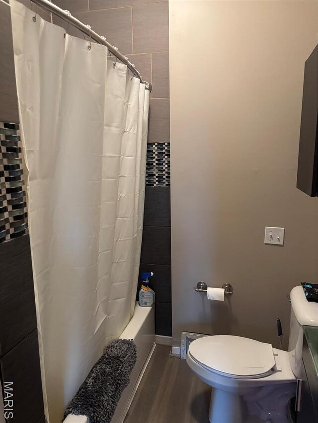 911 Grand Ave, Edwardsville, IL 62025 - bathroom featuring toilet, wood finished floors, and shower / bathtub combination with curtain