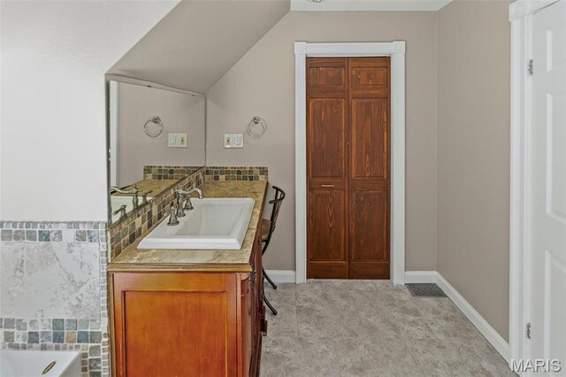 911 Grand Ave, Edwardsville, IL 62025 - full bathroom featuring vanity, a tub to relax in, baseboards, and lofted ceiling