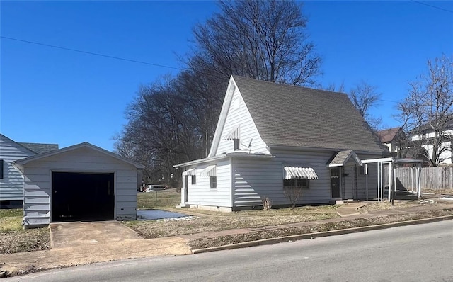 view of property exterior featuring a garage, concrete driveway, roof with shingles, and an outbuilding