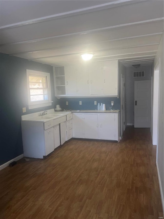 kitchen featuring dark wood-style flooring, white cabinetry, light countertops, and a sink