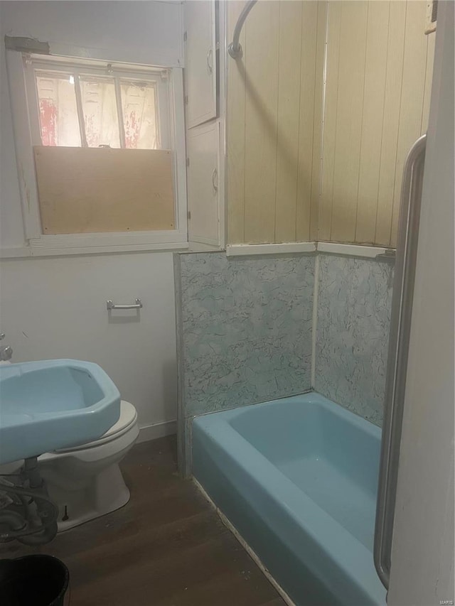 bathroom with a bath, wood finished floors, a sink, and baseboards