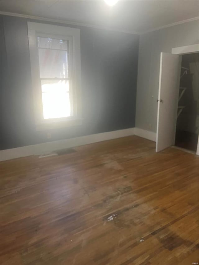 unfurnished bedroom with ornamental molding, wood finished floors, and baseboards