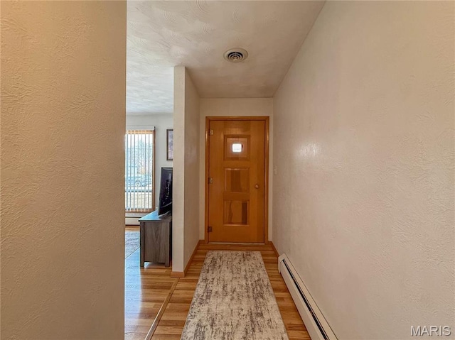 134 Pine St, Farmington, MO 63640 - doorway to outside with light wood-type flooring, a textured wall, a baseboard radiator, and baseboards