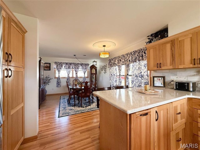 134 Pine St, Farmington, MO 63640 - kitchen with light wood-type flooring, a peninsula, light stone countertops, decorative light fixtures, and baseboards