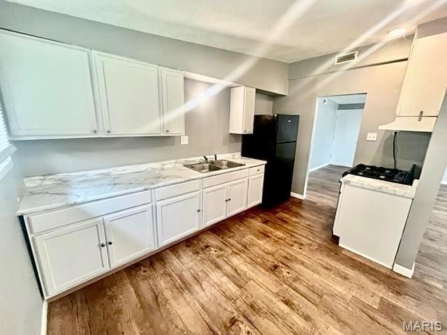 750 Robinwood Dr, Florissant, MO 63033 - kitchen with freestanding refrigerator, wood finished floors, white cabinets, and gas range gas stove
