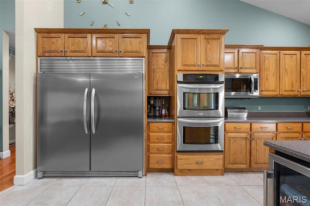 149 Windy Point Ave, Cape Girardeau, MO 63701 - kitchen featuring stainless steel appliances, beverage cooler, brown cabinetry, dark countertops, and lofted ceiling