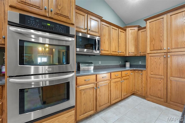 149 Windy Point Ave, Cape Girardeau, MO 63701 - kitchen with stainless steel appliances, vaulted ceiling, light tile patterned floors, brown cabinets, and a textured ceiling