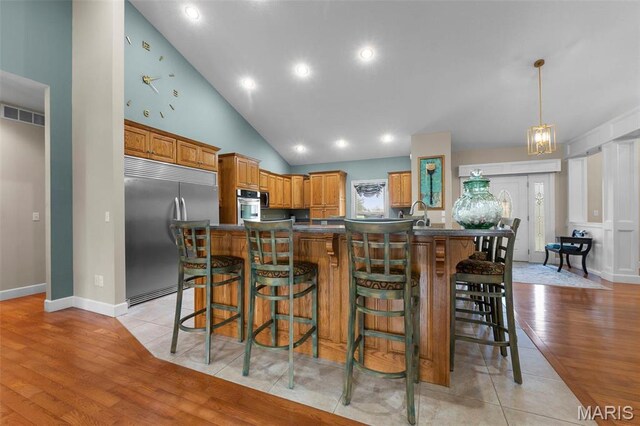 149 Windy Point Ave, Cape Girardeau, MO 63701 - kitchen featuring stainless steel appliances, a kitchen breakfast bar, light wood-style floors, dark countertops, and high vaulted ceiling