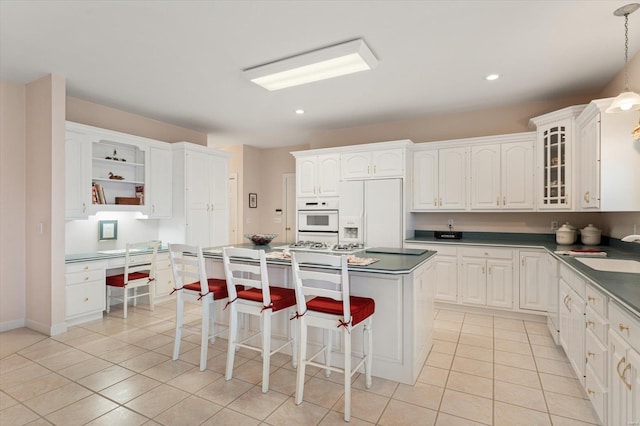 230 W Waters Edge Dr, Belleville, IL 62221 - kitchen with white appliances, dark countertops, light tile patterned floors, white cabinetry, and a sink