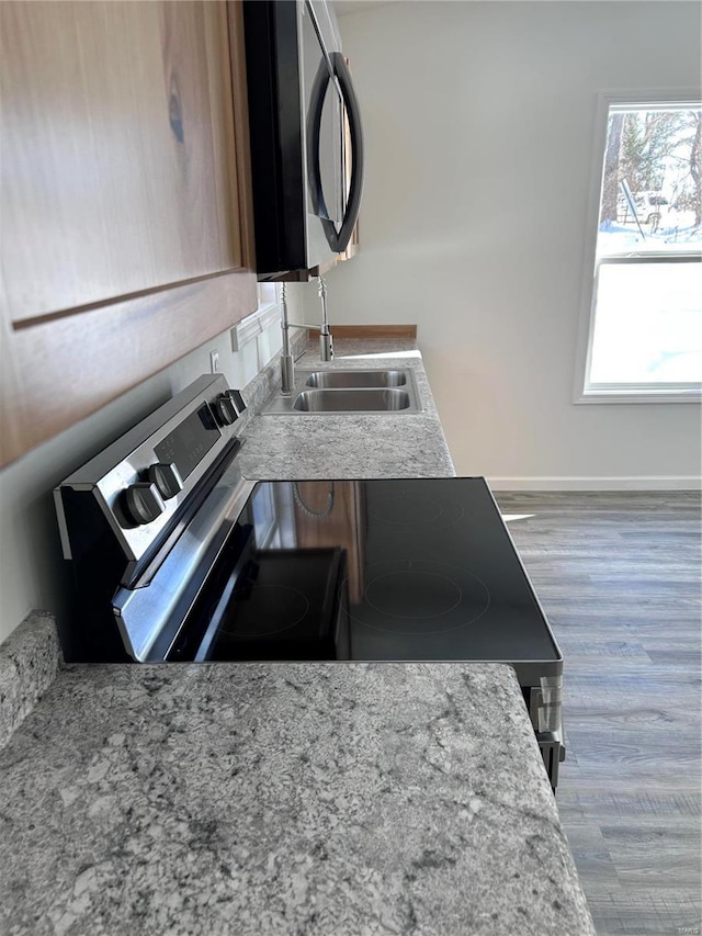 1510 N Mapleshade Rd, Cuba, MO 65453 - kitchen view of appliances with stainless steel finishes, wood finished floors, a sink, baseboards, and light stone countertops