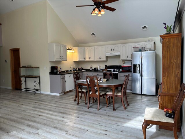 dining space with ceiling fan, high vaulted ceiling, light wood finished floors, and baseboards