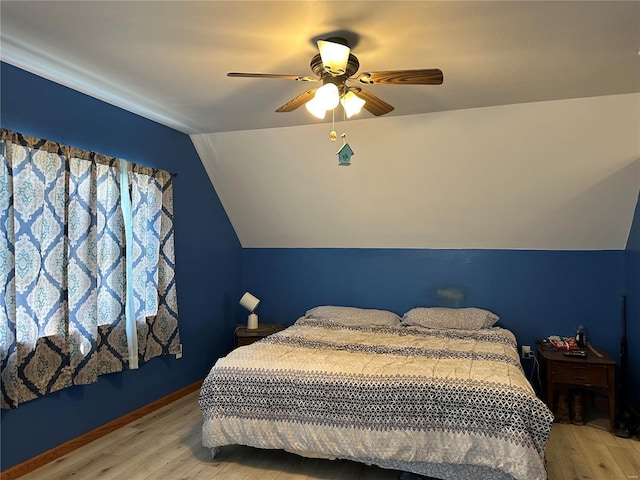 bedroom featuring light wood-style floors, lofted ceiling, a ceiling fan, and baseboards