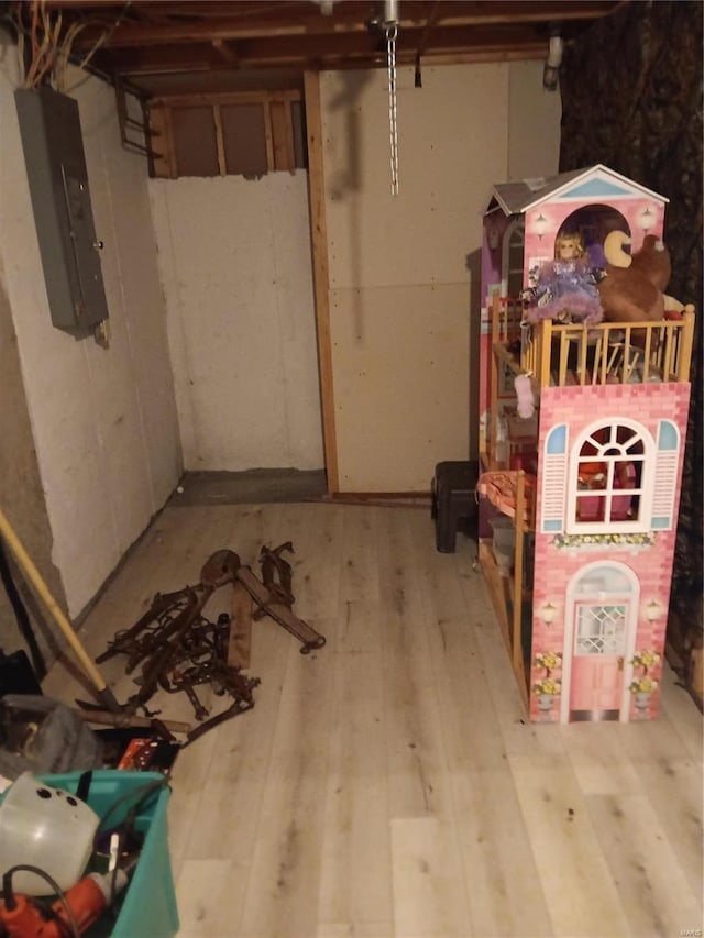 below grade area with electric panel and light wood-type flooring