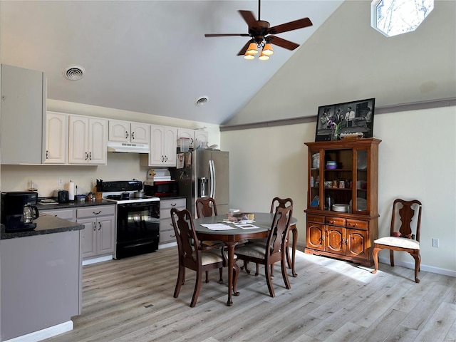 kitchen with black appliances, under cabinet range hood, dark countertops, light wood-style floors, and high vaulted ceiling