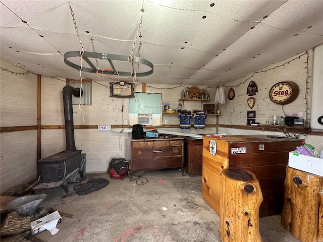 kitchen featuring concrete floors, a wood stove, and wooden walls