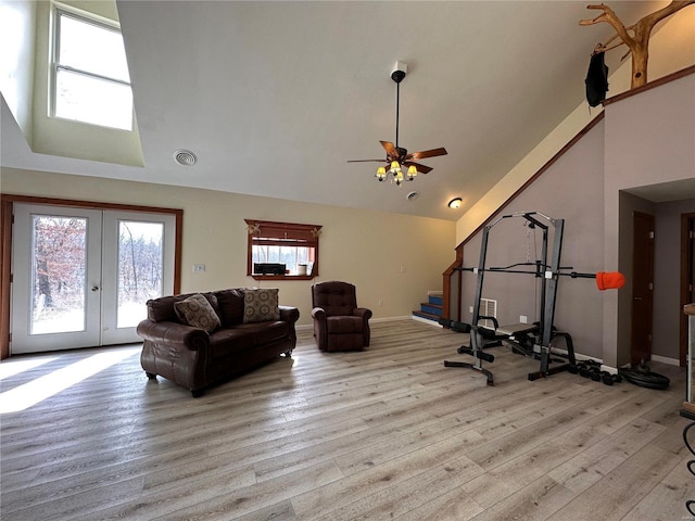 living room featuring wood finished floors, stairway, a ceiling fan, french doors, and high vaulted ceiling
