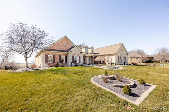 view of front facade with a front yard, brick siding, and stone siding