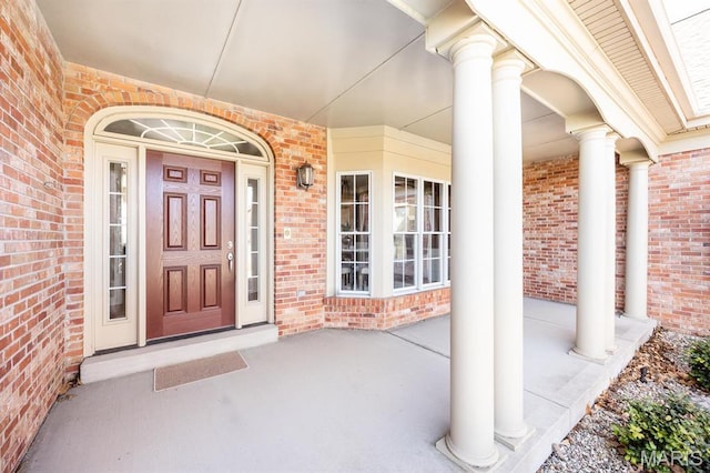 doorway to property with covered porch and brick siding
