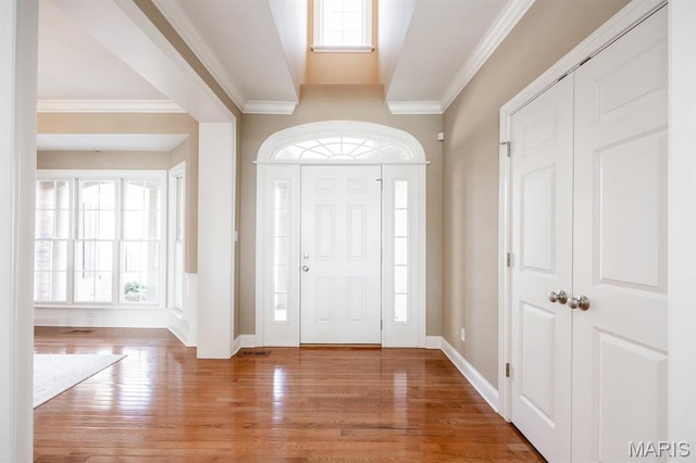 foyer entrance featuring wood finished floors, crown molding, and baseboards