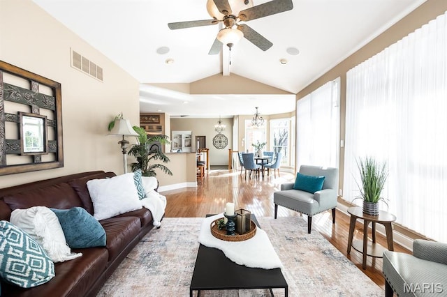 living room featuring wood finished floors, a ceiling fan, baseboards, and a chandelier