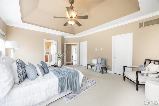 bedroom featuring a raised ceiling, light colored carpet, crown molding, a ceiling fan, and ensuite bath