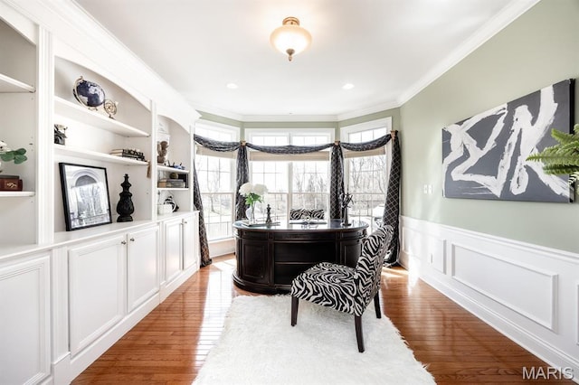 office space featuring crown molding, wood finished floors, healthy amount of natural light, wainscoting, and a decorative wall