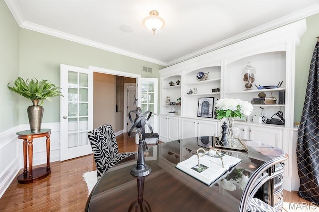 office with french doors, wood finished floors, ornamental molding, wainscoting, and built in shelves
