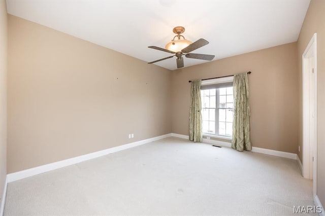 spare room featuring light colored carpet, baseboards, and ceiling fan