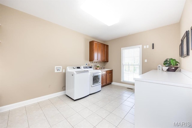 laundry room featuring separate washer and dryer, cabinet space, light tile patterned floors, and baseboards