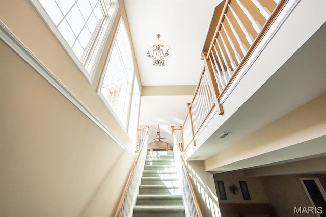 staircase featuring a high ceiling, a chandelier, and ceiling fan