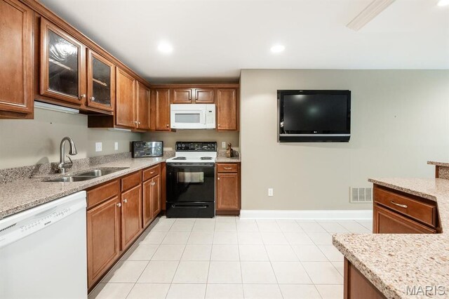 kitchen with white appliances, a sink, brown cabinetry, glass insert cabinets, and recessed lighting