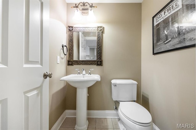 bathroom with tile patterned flooring, baseboards, toilet, and a sink