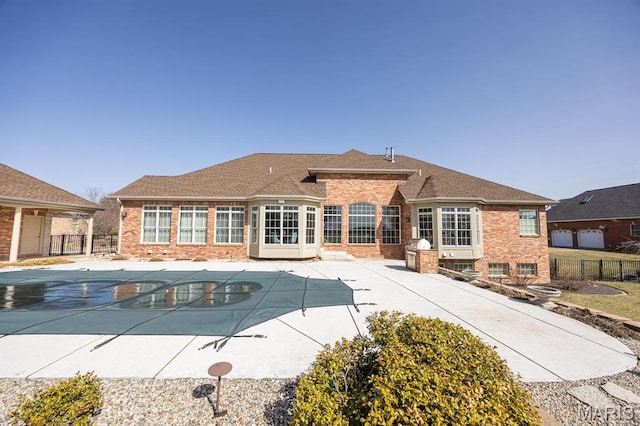back of property with fence, brick siding, and a patio