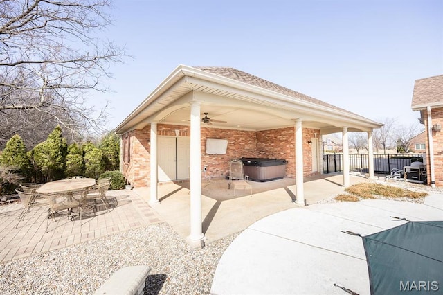 view of patio featuring a hot tub, ceiling fan, and fence