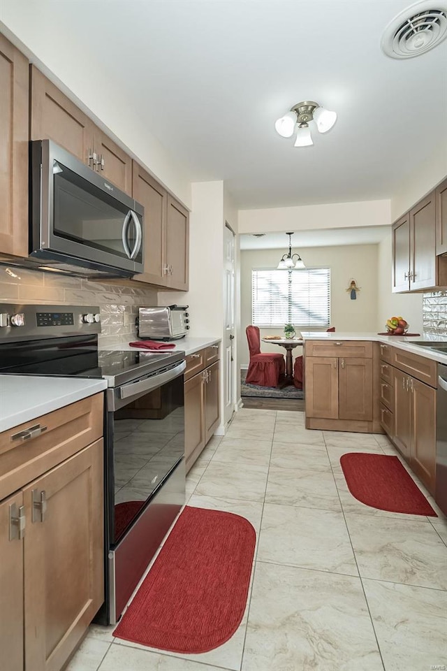 1611 Walpole Dr Unit C, Chesterfield, MO 63017 - kitchen featuring stainless steel appliances, tasteful backsplash, light countertops, hanging light fixtures, and a peninsula
