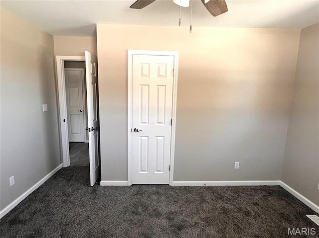 unfurnished bedroom with dark colored carpet, baseboards, and a ceiling fan